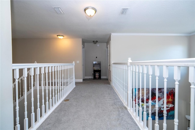 corridor with ornamental molding, light carpet, and a textured ceiling