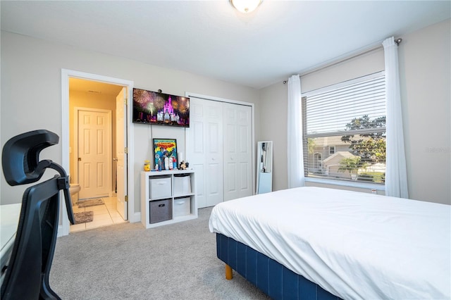 bedroom featuring light carpet, ensuite bath, and a closet