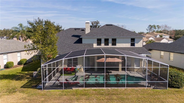 rear view of house with a patio, glass enclosure, and a lawn