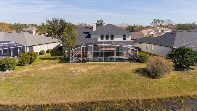 back of house with a yard and glass enclosure