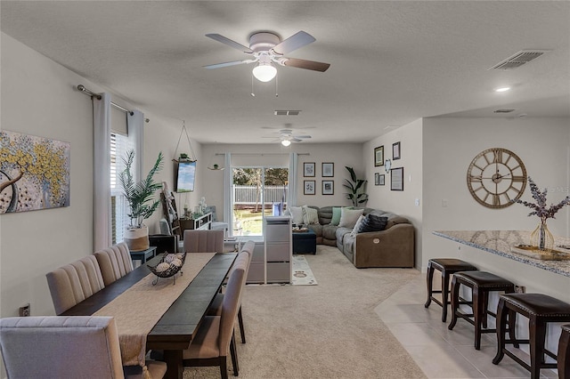 dining space with light colored carpet and a textured ceiling