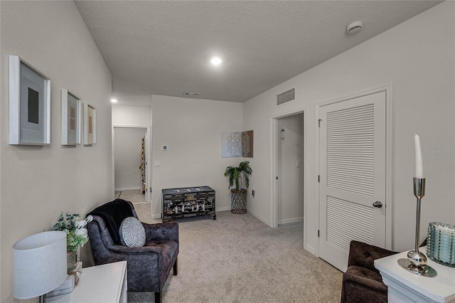 sitting room with light colored carpet and a textured ceiling