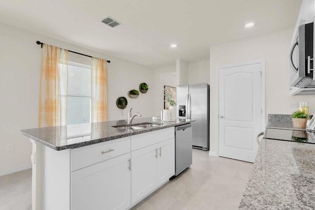 kitchen with stone countertops, white cabinetry, an island with sink, sink, and stainless steel appliances