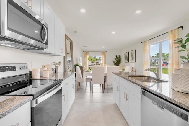 kitchen with white cabinetry, sink, light tile patterned floors, light stone counters, and stainless steel appliances