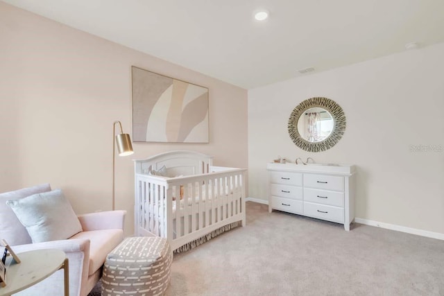 bedroom with a nursery area and light carpet