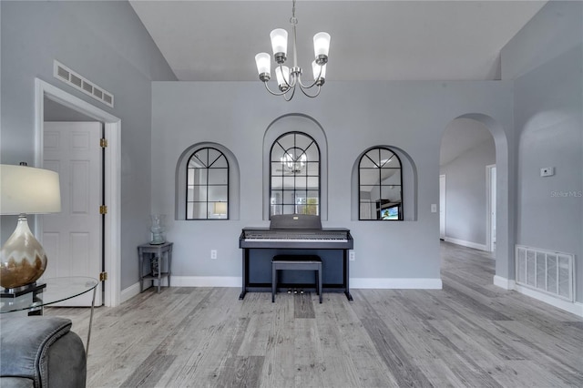 unfurnished room with a notable chandelier, visible vents, arched walkways, and wood finished floors