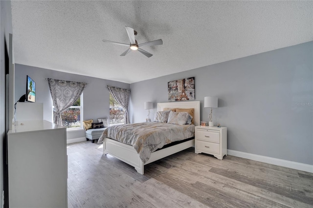 bedroom with baseboards, a textured ceiling, light wood-style flooring, and a ceiling fan