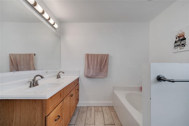 full bath with a sink, wood finished floors, double vanity, and a bath