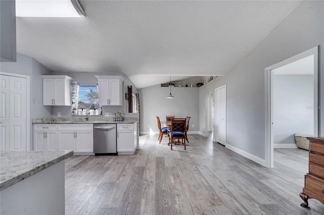 kitchen with light stone counters, stainless steel dishwasher, white cabinetry, light wood-style floors, and lofted ceiling