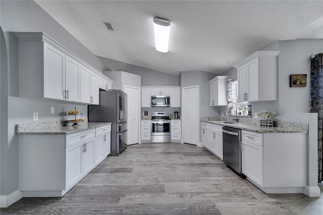 kitchen with light wood-type flooring, stainless steel appliances, visible vents, and white cabinets