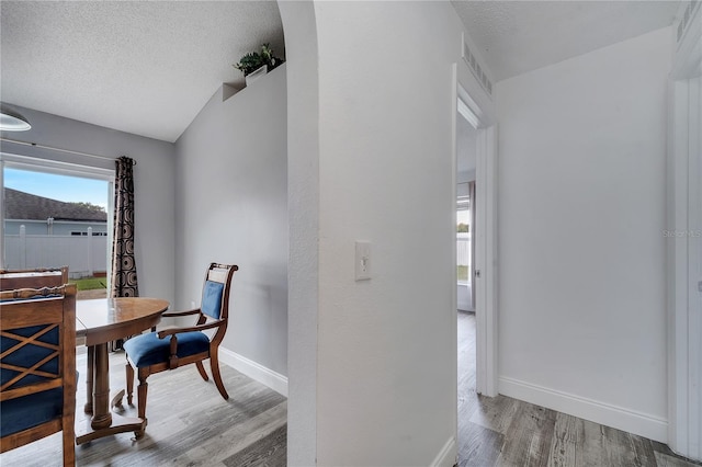 dining area featuring wood finished floors, baseboards, and a textured ceiling