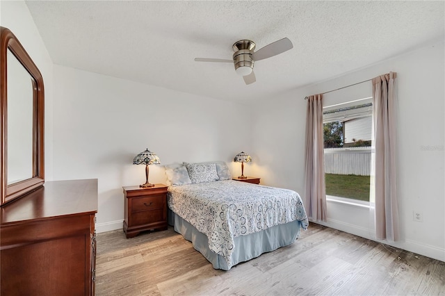 bedroom with light wood-type flooring, baseboards, and a textured ceiling