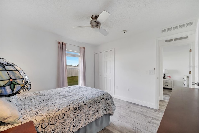 bedroom with a textured ceiling, visible vents, a closet, and light wood-type flooring