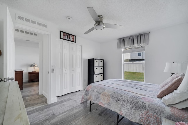 bedroom featuring wood finished floors, visible vents, a closet, and a textured ceiling