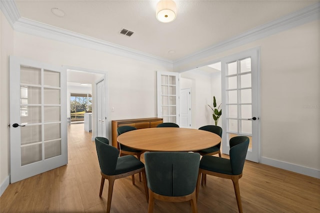 dining area featuring french doors, crown molding, and hardwood / wood-style flooring