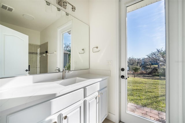 bathroom featuring vanity, a wealth of natural light, and a tile shower