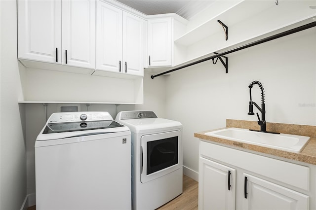 washroom featuring cabinets, light hardwood / wood-style floors, sink, and washing machine and dryer