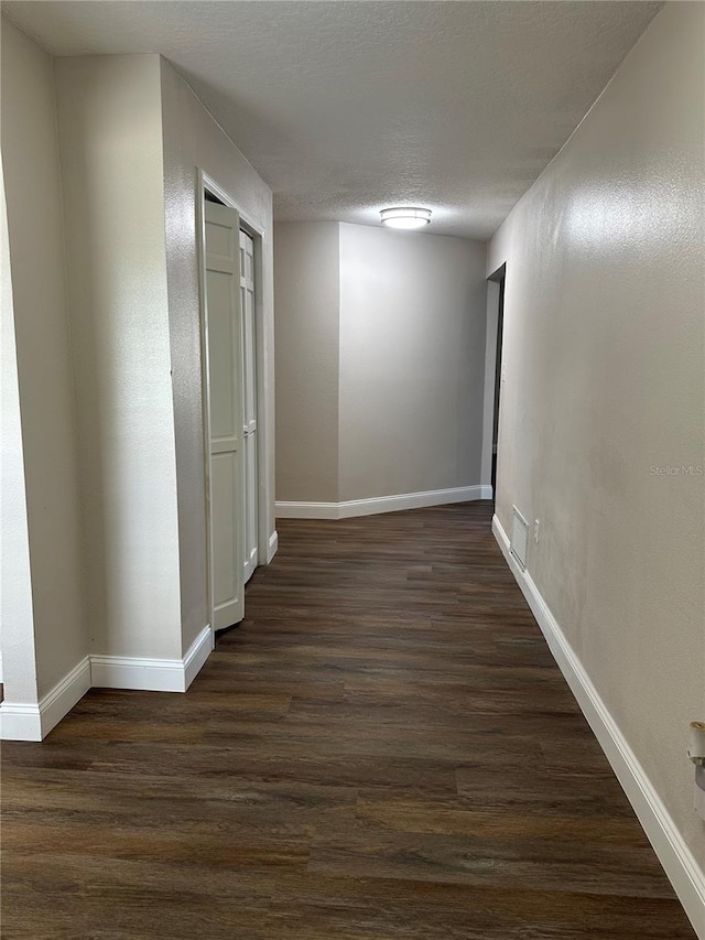 hallway with dark wood-type flooring and a textured ceiling