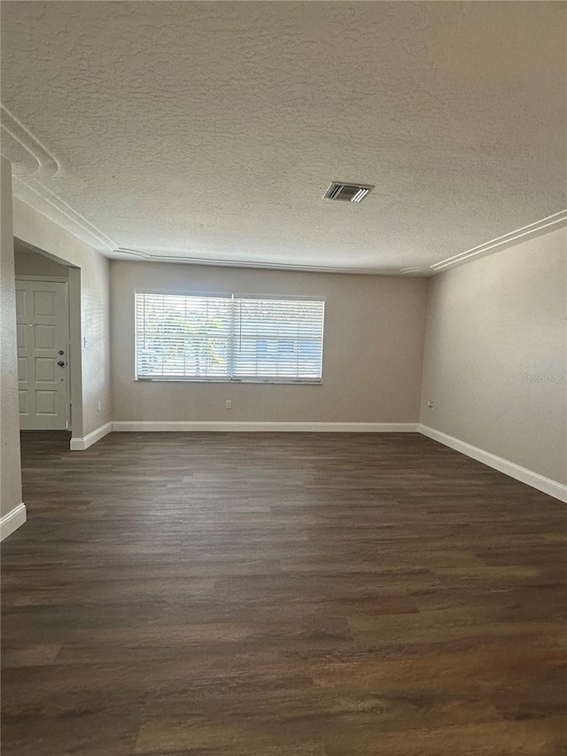 spare room featuring crown molding, dark hardwood / wood-style floors, and a textured ceiling