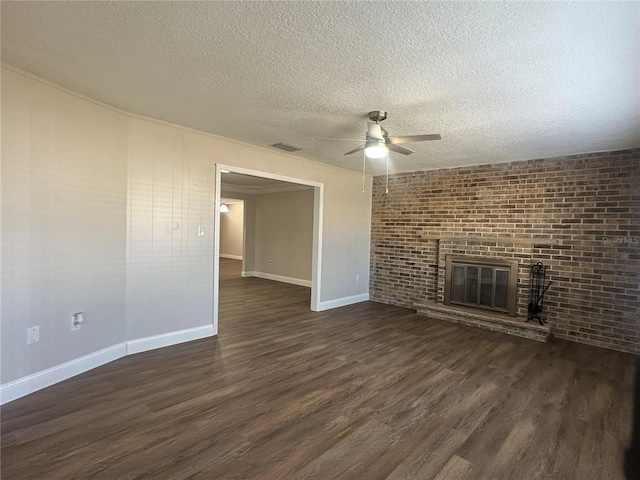 unfurnished living room with a brick fireplace, a textured ceiling, dark wood-type flooring, and ceiling fan