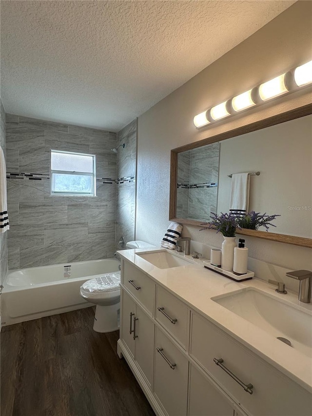 full bathroom featuring toilet, tiled shower / bath, a textured ceiling, vanity, and hardwood / wood-style flooring