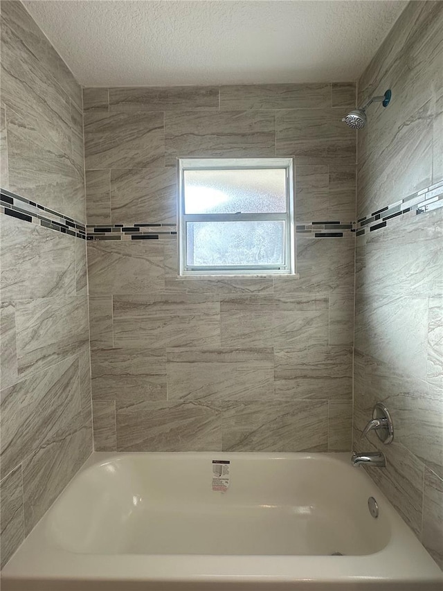 bathroom with tiled shower / bath combo and a textured ceiling