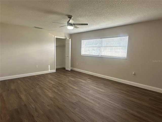 unfurnished bedroom with dark wood-type flooring, a textured ceiling, ceiling fan, and a closet