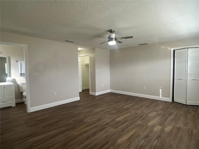 unfurnished bedroom with ceiling fan, ensuite bath, dark hardwood / wood-style floors, and a textured ceiling