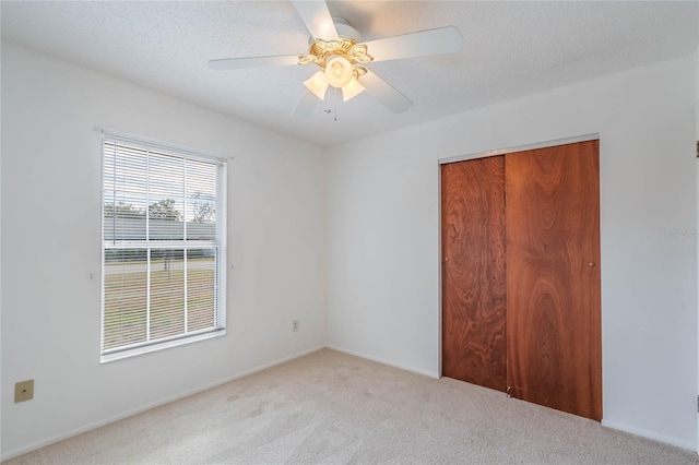 carpeted empty room with a textured ceiling and ceiling fan