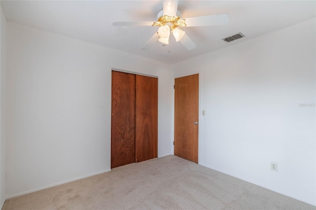 unfurnished bedroom with ceiling fan, carpet flooring, and a closet