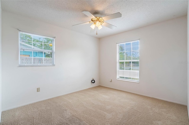 empty room with ceiling fan, light colored carpet, and a textured ceiling