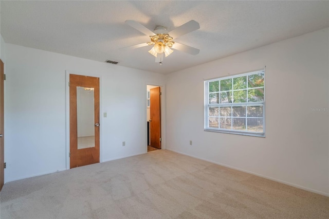 carpeted spare room with ceiling fan and a textured ceiling