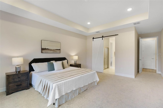 bedroom featuring a tray ceiling, light colored carpet, and a barn door