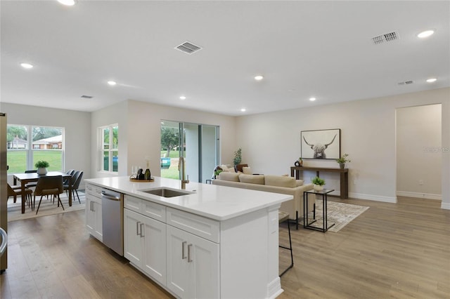 kitchen with sink, white cabinetry, dishwasher, a kitchen island with sink, and light hardwood / wood-style floors