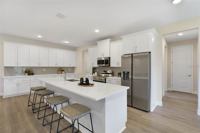 kitchen featuring sink, a breakfast bar area, white cabinets, and appliances with stainless steel finishes