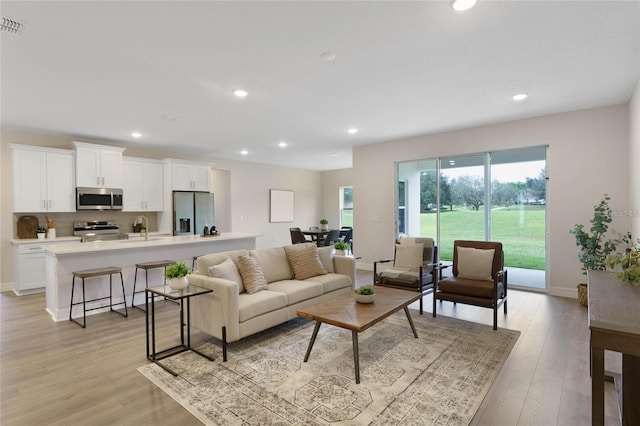 living room featuring sink and light hardwood / wood-style flooring