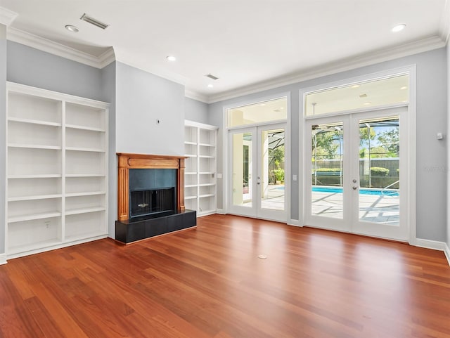 unfurnished living room featuring crown molding, hardwood / wood-style floors, built in features, and french doors