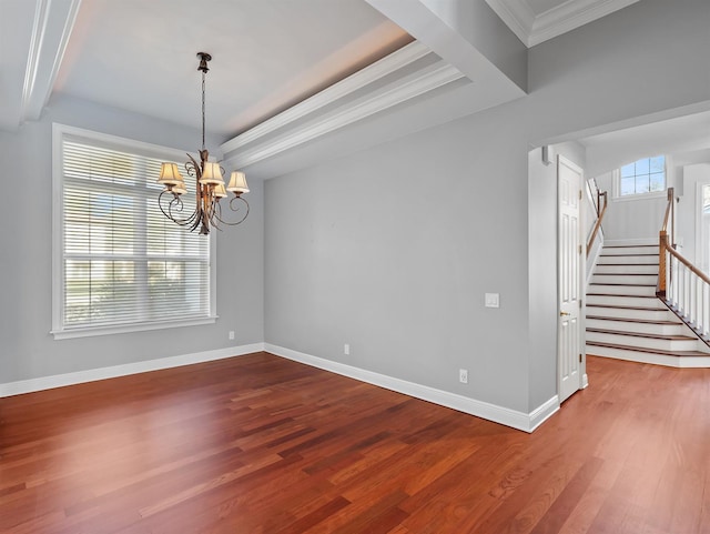 spare room featuring wood-type flooring, ornamental molding, a raised ceiling, and a chandelier