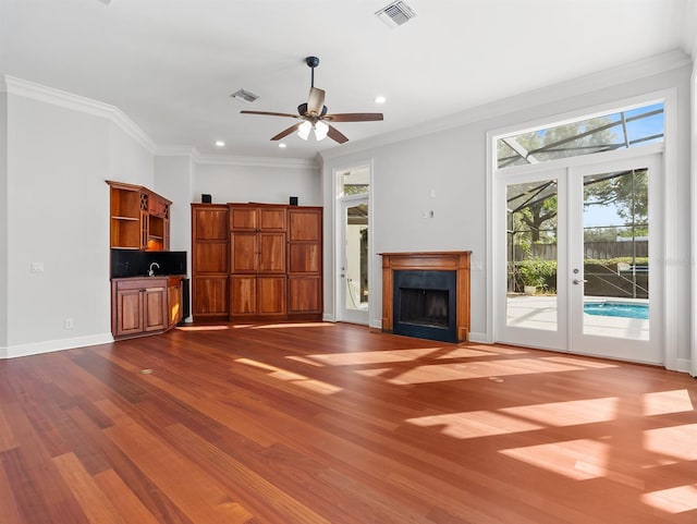 unfurnished living room featuring french doors, ceiling fan, crown molding, and hardwood / wood-style floors