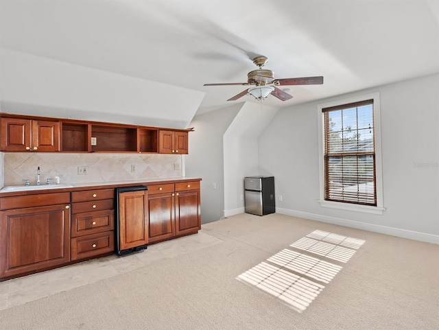 kitchen featuring sink, ceiling fan, backsplash, vaulted ceiling, and light colored carpet