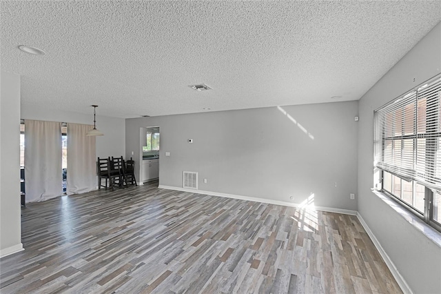 unfurnished living room featuring hardwood / wood-style floors and a textured ceiling