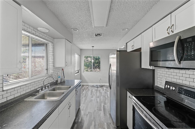 kitchen with sink, stainless steel appliances, white cabinets, and light wood-type flooring