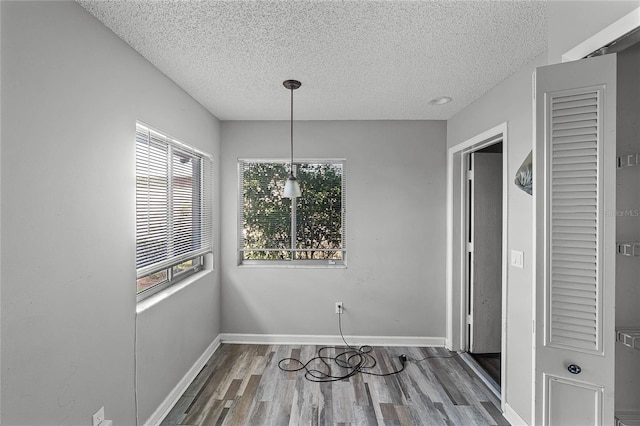 unfurnished dining area featuring dark wood-type flooring and a textured ceiling