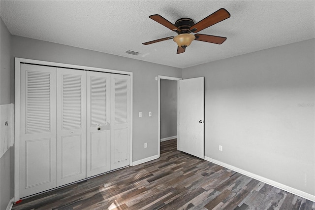 unfurnished bedroom featuring a closet, dark hardwood / wood-style floors, a textured ceiling, and ceiling fan