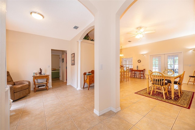 hall featuring decorative columns, light tile patterned flooring, and vaulted ceiling