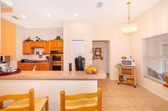 kitchen with decorative light fixtures, kitchen peninsula, double oven, and light tile patterned floors