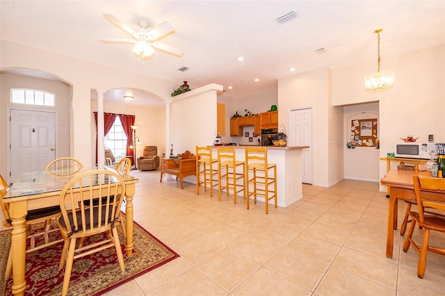 tiled dining room featuring ceiling fan and decorative columns