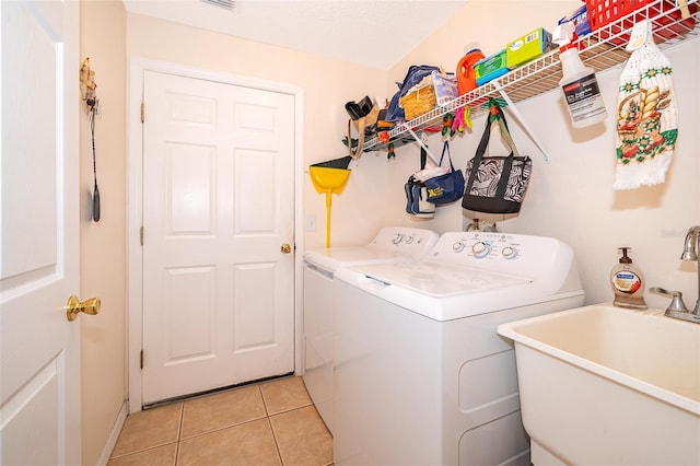 washroom featuring washing machine and dryer, sink, and light tile patterned floors