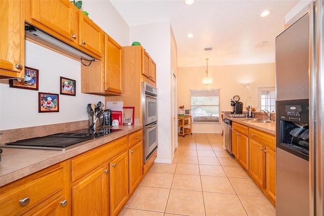 kitchen with light countertops, a sink, brown cabinetry, light tile patterned floors, and stainless steel appliances