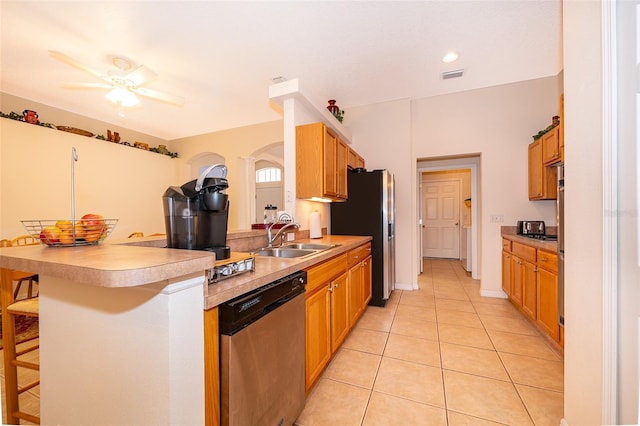 kitchen with a kitchen breakfast bar, a sink, ceiling fan, a peninsula, and appliances with stainless steel finishes
